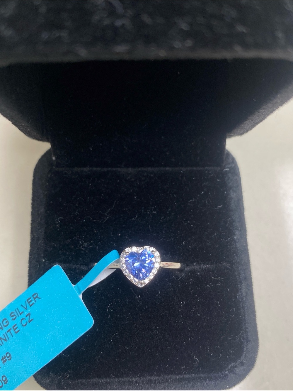Blue tanzanite heart shaped ring with silver band and cubic zirconia halo
Size 9